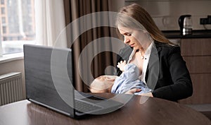 Young caucasian mother working remotely on laptop at home breastfeeding baby, caring and feeding newborn, happy