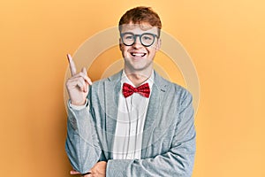 Young caucasian nerd man wearing glasses wearing hipster elegant look with bowtie smiling happy pointing with hand and finger to