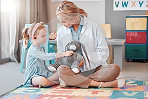 Young caucasian paediatrician helping a little girl listen to the heartbeat of a toy with a stethoscope, Small, happy