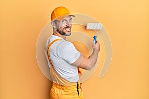 Young caucasian painter smiling happy painting wall using roller