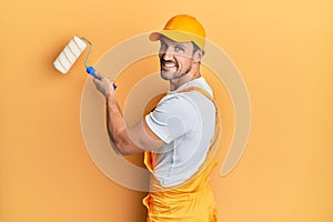 Young caucasian painter smiling happy painting wall using roller