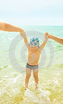 Young caucasian parents mother and father hold by hands their baby toddler son. Touching emotional scene. Family togetherness