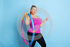 Young caucasian plus size female model`s training on blue background