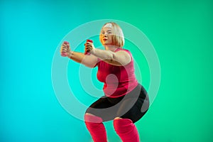 Young caucasian plus size female model`s training on gradient green background
