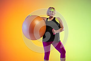 Young caucasian plus size female model`s training on gradient orange background