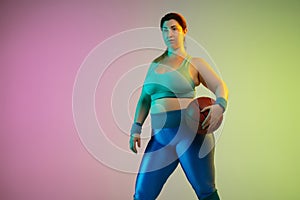 Young caucasian plus size female model`s training on gradient purple green background