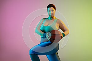 Young caucasian plus size female model`s training on gradient purple green background