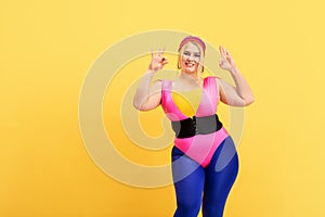 Young caucasian plus size female model`s training on yellow background