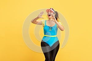 Young caucasian plus size female model`s training on yellow background