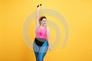 Young caucasian plus size female model`s training on yellow background