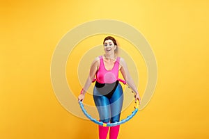 Young caucasian plus size female model`s training on yellow background