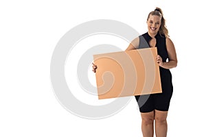 A young Caucasian plus size model holds blank sign, smiling on a white background, copy space