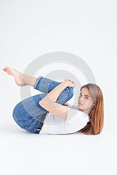 young caucasian pretty girl in t-shirt and jeans lifting her legs, holding knees