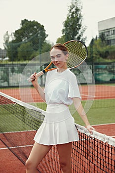 Young caucasian professional female tennis player near tennis net