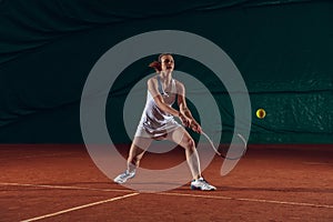 Young caucasian professional sportswoman playing tennis on sport court background