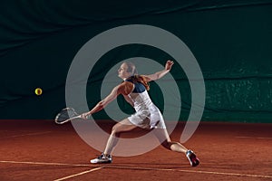 Young caucasian professional sportswoman playing tennis on sport court background