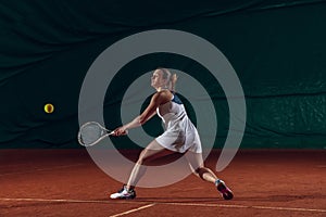 Young caucasian professional sportswoman playing tennis on sport court background