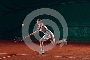 Young caucasian professional sportswoman playing tennis on sport court background