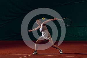 Young caucasian professional sportswoman playing tennis on sport court background