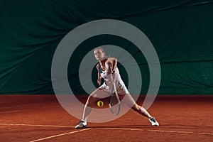 Young caucasian professional sportswoman playing tennis on sport court background