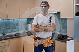 Young caucasian repairman in face mask working with furniture