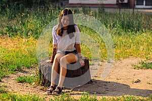 Young caucasian smiling woman  is sitting on a stump