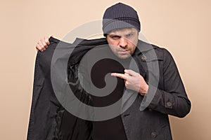 Young caucasian speculator man pointing on his coat on empty place hiding deficit food