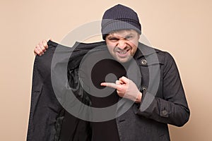 Young caucasian speculator man pointing on his coat on empty place hiding deficit food