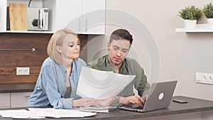 Young caucasian spouses sitting with laptop and documents