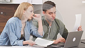 Young caucasian spouses sitting with laptop and documents