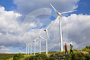 Young engineers looking and checking wind turbines at field