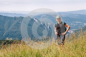 Young caucasian teenage male backpacker walking in hight grass by Mala Fatra mountain range in Slovakian Tatry and enjoying the