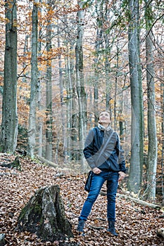 Young caucasian tourist woman is looking around in autumn forest