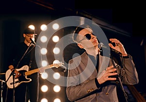 Young Caucasian vocalist sings against the backdrop of a garage band