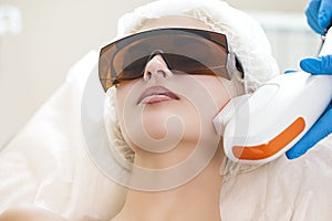 Young Caucasian Winsome Woman Getting IPL Laser and Ultrasound Facial Treatment in Modern Medical Spa Center As Skin Rejuvenation photo