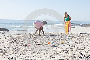 Young Caucasian woman and African American man clean a beach by collecting trash with copy space