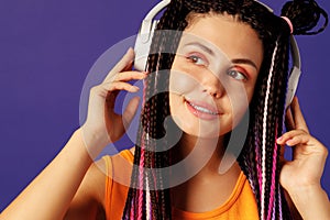 Young caucasian woman with african cornrows listening to music with headphones