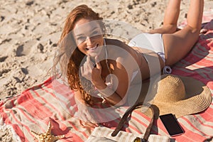 Young Caucasian woman in bikini lying on sand and looking at camera on the beach