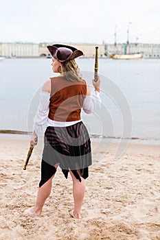 Young Caucasian woman in black and brown pirate costume raised toy gun