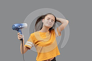 Young caucasian woman blow-dry hair isolated on gray background