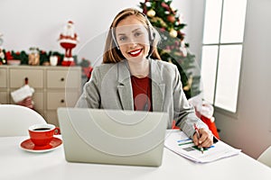Young caucasian woman call center agent working sitting by christmas tree at home