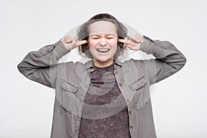 Young caucasian woman in casual clothes closing her ears