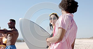 Young Caucasian woman chats with a young Biracial man at the beach