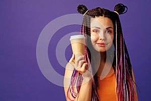 Young caucasian woman with colorful long cornrows holding a cup of coffee against purple background