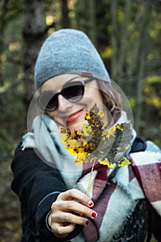 Young caucasian woman with colorful maple leaf in autumn nature