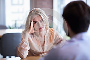 Young Caucasian woman disinterested in blind date, feeling bored with conversation at city cafe