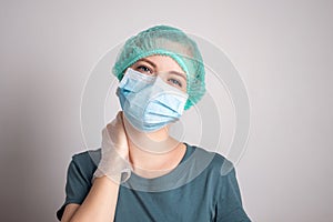 Young caucasian woman doctor nurse in surgical mask looks tired