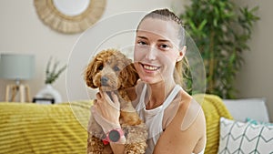 Young caucasian woman with dog playing sitting on the sofa at home