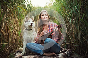 Young caucasian woman with dog playing ukulele