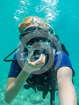 Young caucasian  woman dressed in diving equipment swimming underwater in ionian sea .Greece , Corfu scuba diving in vacation